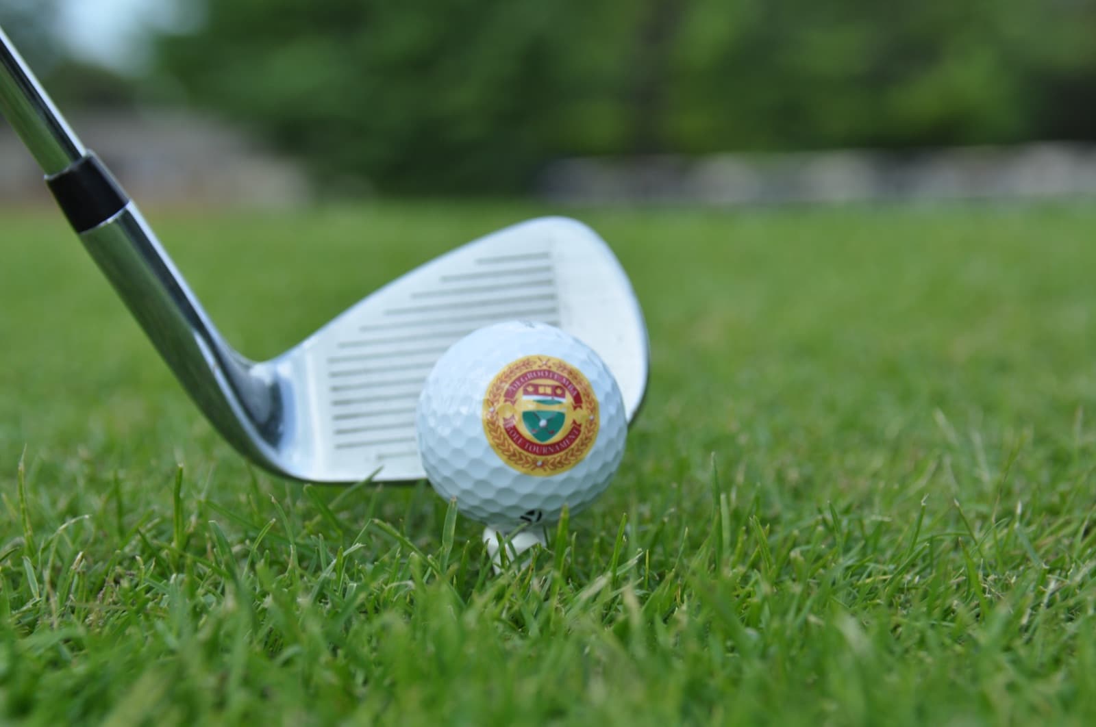 Close-up of an iron behind a golf ball carrying the tournament crest