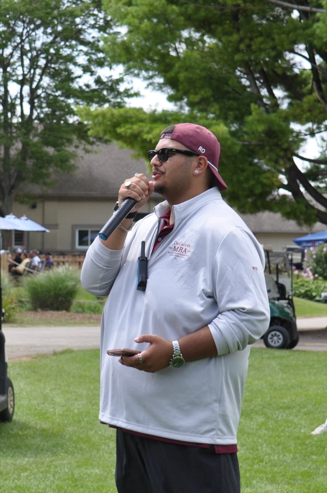 Committee member in a quarter-zip addressing the field on the microphone