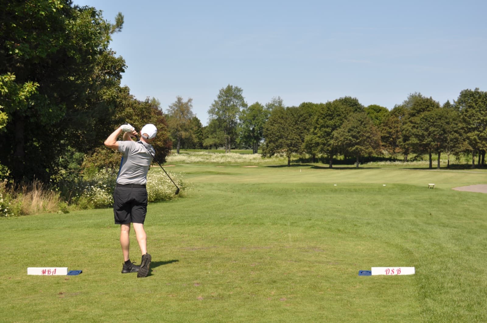 Golfer mid follow-through between the MBA and DSB tee blocks
